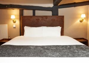 a bedroom with a large bed with white sheets at Bull Hotel by Greene King Inns in Halstead
