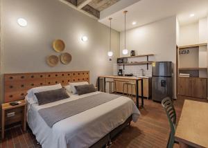 a bedroom with a large bed and a kitchen at The Somos Flats Laureles in Medellín