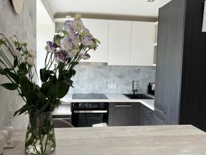 a vase of flowers sitting on a table in a kitchen at Cozy apartment in Jūrmala
