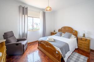 ein Schlafzimmer mit einem großen Bett und einem Stuhl in der Unterkunft CASA AMARELA in Charneca
