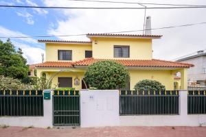 ein gelbes Haus mit einem schwarzen Zaun in der Unterkunft CASA AMARELA in Charneca