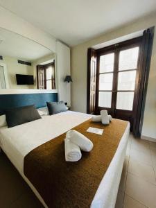 two beds in a hotel room with towels on them at Miguel De Cervantes in Alcalá de Henares