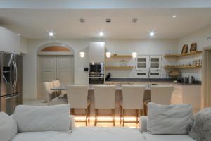 una cocina con sillas blancas y una mesa y una cocina con encimera. en Luxury 4 bed villa in Mullins St Peter - Sugar Palm House, en Saint Peter