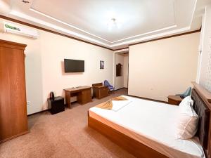 Schlafzimmer mit einem Bett, einem Schreibtisch und einem TV in der Unterkunft Hotel Khiva Palace in Xiva