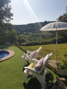 two chairs and an umbrella next to a pool at Casa Rural O Bergando in Cotobade