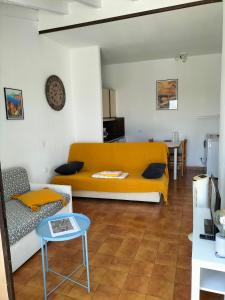 un soggiorno con divano giallo e tavolo di Studio vue mer à Porticcio proche aéroport Ajaccio a Porticcio