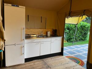 a kitchen with white cabinets and a sink in a tent at Camping Engelbert (Groningen) in Groningen