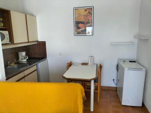 una piccola cucina con un tavolino e un tavolino con una coperta gialla di Studio vue mer à Porticcio proche aéroport Ajaccio a Porticcio