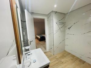 een witte badkamer met een wastafel en een douche bij corail royal hotel in Tabarka