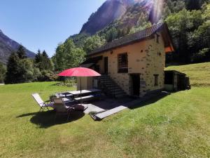 een huis met een tafel en stoelen en een paraplu bij Ca da Lovi in Cerentino