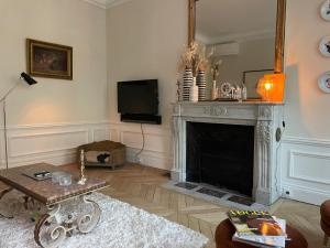 a living room with a fireplace and a tv at Paris 8 golden triangle - fancy brand new appt in historic building in Paris