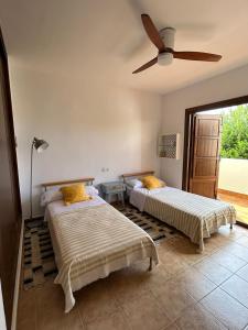 um quarto com 2 camas e uma ventoinha de tecto em Casa con piscina en San José Sotillo em San José