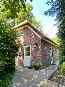 una casa de ladrillo con una puerta blanca en Huisje aan de Bosrand - Veluwe, en Epe