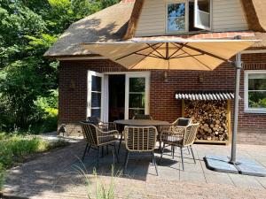 einen Tisch und Stühle mit Sonnenschirm auf einer Terrasse in der Unterkunft Huisje aan de Bosrand - Veluwe in Epe