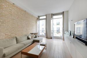 a living room with a couch and a brick wall at Appartement Neuf Saint-Honoré - Tuileries in Paris