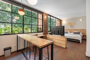 a bedroom with a bed and a tv in a room with windows at The Somos Flats Laureles in Medellín