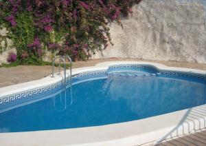 una piscina en un patio con flores púrpuras en Ada Calypso Apartamento, frente al mar y castillo, Parking, Aire acondicionado, WiFi, Piscina, en Peñíscola