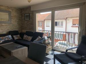 a living room with a couch and a balcony at Quartier calme, terrasse plein sud, jardin, spa en option in Étaples