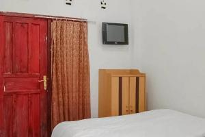 una camera da letto con una porta rossa e una TV a parete di Homestay Cantika Koto Tengah RedPartner a Sungaipenuh