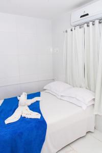 a white bed with a teddy bear on a blue blanket at Pousada Sereias de Maragogi in Ponta do Mangue