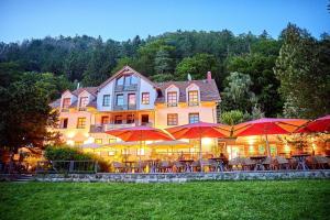 une grande maison avec des tables et des parasols en face de celle-ci dans l'établissement Bio-Hotel Helvetia, à Bad Schandau