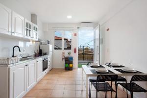 a kitchen with white cabinets and a table and chairs at Babosas Charm in Funchal