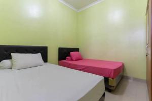 twee bedden in een kamer met roze en witte lakens bij Kostawira Syariah Bintaro Mitra RedDoorz in Mencil