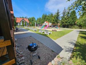 a grill in a yard with a playground at Ogrzewane Domki u Kamili Sztutowo, Jacuzzi, plac zabaw, klimatyzacja, parking# 884#90#09#01 in Sztutowo