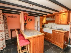 Una cocina con gabinetes de madera y encimera. en The Old Forge Cottage, en Bude