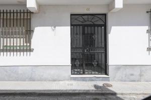 um edifício branco com uma porta e vedação pretas em Calana em San Fernando