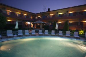 um hotel com uma grande piscina com cadeiras e guarda-sóis em Hotel Zeus em Afitos