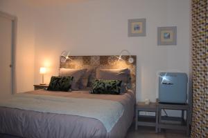 ein Schlafzimmer mit einem großen Bett und einem TV in der Unterkunft Ici et Là - Chambres d'hôtes in Velleron
