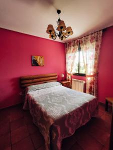 ein Schlafzimmer mit einem Bett mit einer roten Wand in der Unterkunft La Pérgola in La Cabrera