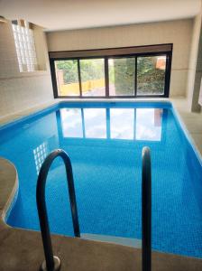 a large swimming pool with blue tiles in a building at La Pérgola in La Cabrera