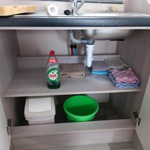 a sink with a bottle of coke sitting under a sink at Caravan Aan Zee Arnani in Middelkerke +85 photos