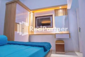 a bedroom with a blue bed and a tv at Hotel Rai's Palopo Exclusive Mitra RedDoorz in Palopo