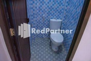 a bathroom with a toilet in a blue tiled stall at Hotel Rai's Palopo Exclusive Mitra RedDoorz in Palopo
