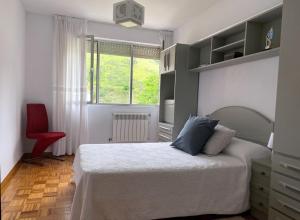a bedroom with a bed and a red chair at Apartamento Venecia in Unquera