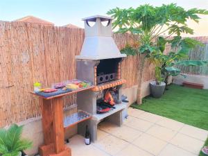 un horno de pizza al aire libre en un patio trasero con una valla en Espacioso apartamento con preciosos jardines y BBQ, en Isla Plana