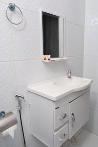 a white bathroom with a sink and a mirror at Pousada Sereias de Maragogi in Ponta do Mangue