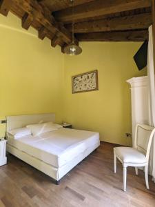 1 dormitorio con 1 cama blanca y 1 silla en Villa Iris, en Mogliano Veneto