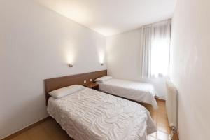 una piccola stanza con due letti e una finestra di La Solana Apartaments & Spa a Encamp