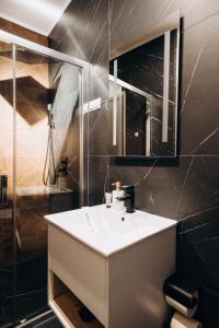 La salle de bains est pourvue d'un lavabo blanc et d'une douche. dans l'établissement Pensiunea Brici Junior, à Cluj-Napoca