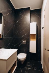 a bathroom with a white toilet and a black wall at Pensiunea Brici Junior in Cluj-Napoca