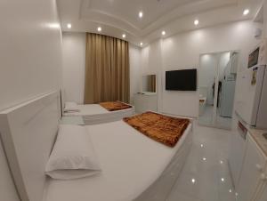 a white room with two beds and a flat screen tv at Al Sabeel Building in Salalah
