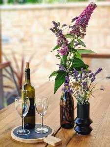 a bottle of wine and two glasses on a table with flowers at Holiday home Smokvin Hlad in Peroj