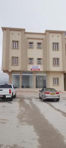two cars parked in a parking lot in front of a building at Al Sabeel Building in Salalah