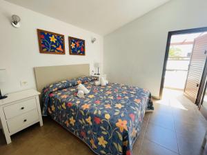 1 dormitorio con 1 cama con colcha de flores y mesita de noche en Estupendo adosado junto al mar, parking, terraza - Los Cancajos en Breña Baja
