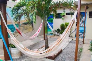 a hammock between two palm trees next to a building at Pousada Sereias de Maragogi in Ponta do Mangue