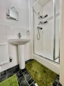 La salle de bains blanche est pourvue d'un lavabo et d'une douche. dans l'établissement Tranquil Haven: 3-BR House, à Great Burstead